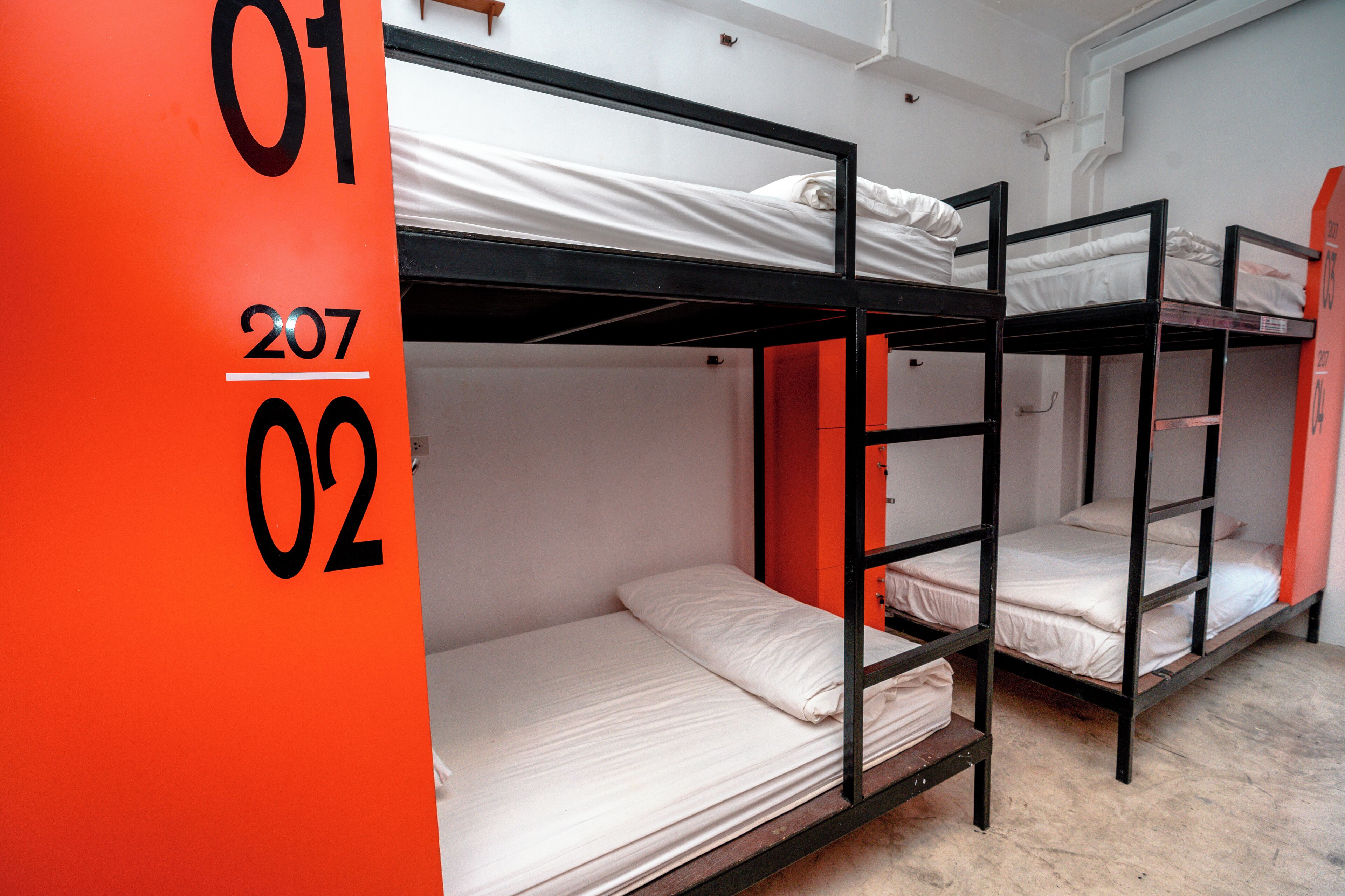 A dormitory with bunk beds, a red wall with numbers, and a white door.