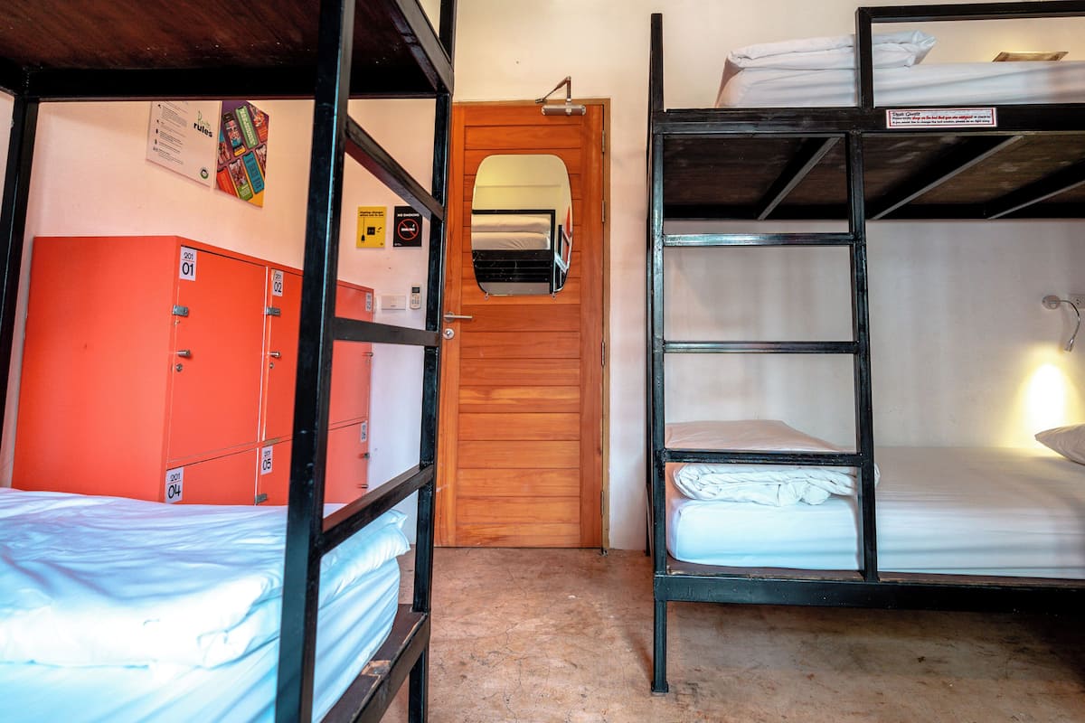 Un dormitorio con literas, una puerta de madera y taquillas anaranjadas.