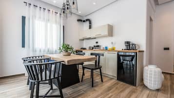 A modern kitchen with a wooden island, black chairs, and a white vase.