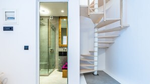 A modern interior with a glass shower, a wooden staircase, and a small wooden stool. - Portes Mykonos Suites & Villas (Mykonos)