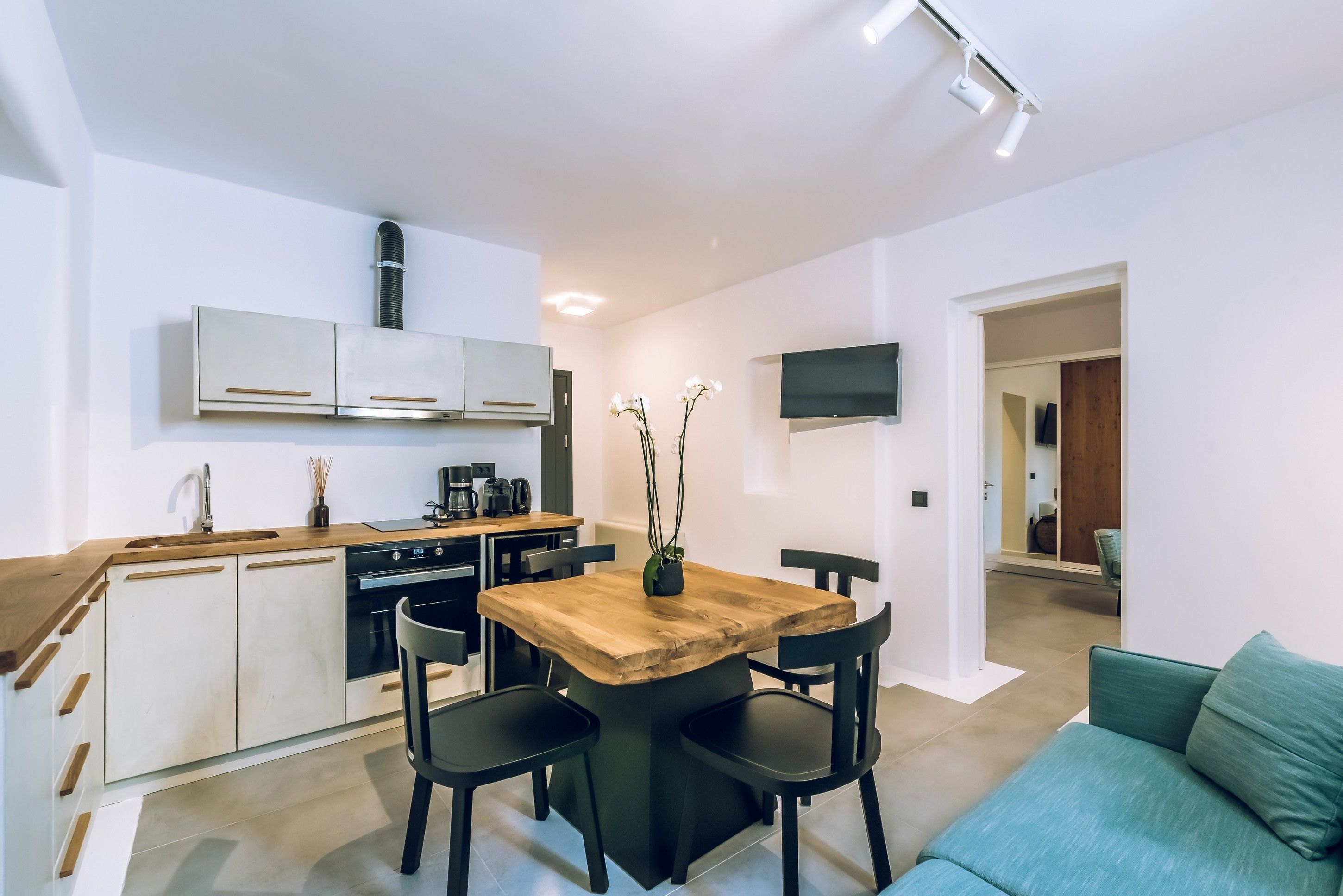 A modern kitchen with white cabinets, a wooden dining table, and black chairs.