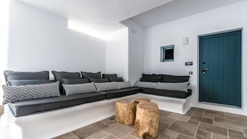 A modern living room with a sectional sofa, wooden stools, and a teal door.