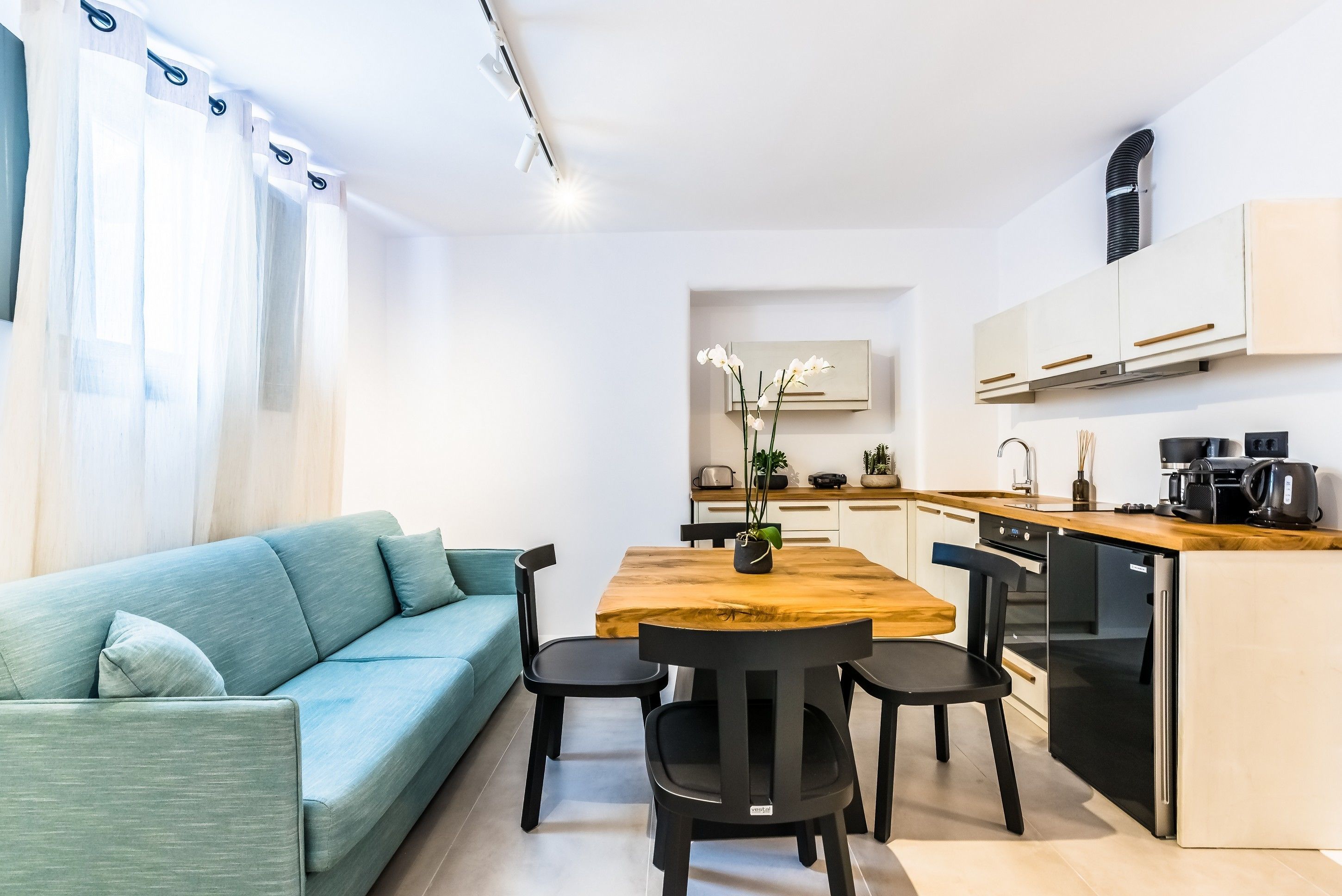 Eine moderne Küche mit einem Holztisch und Stühlen, einem eingebauten Backofen und einem Kühlschrank.
