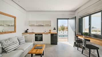 A modern kitchen with white cabinets, a wooden countertop, and a built-in oven. There is a dining area with a wooden table and chairs, and a large window offering a view of the outdoors.