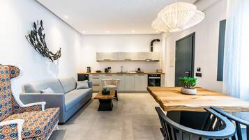 A modern living room with a sofa, a dining table, and a kitchen in the background.
