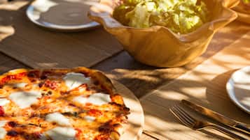 Pizza auf einem Holzteller mit Salat in einer Schüssel auf dem Tisch.