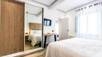 Ein modernes Schlafzimmer mit einem großen Bett, einem Holzschrank, einem Schreibtisch und einem Spiegel.