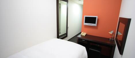 Habitación de hotel con cama, escritorio, silla, televisor y teléfono.