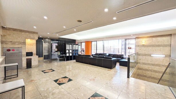 Um hall amplo com balcão de recepção, área de estar e escada.