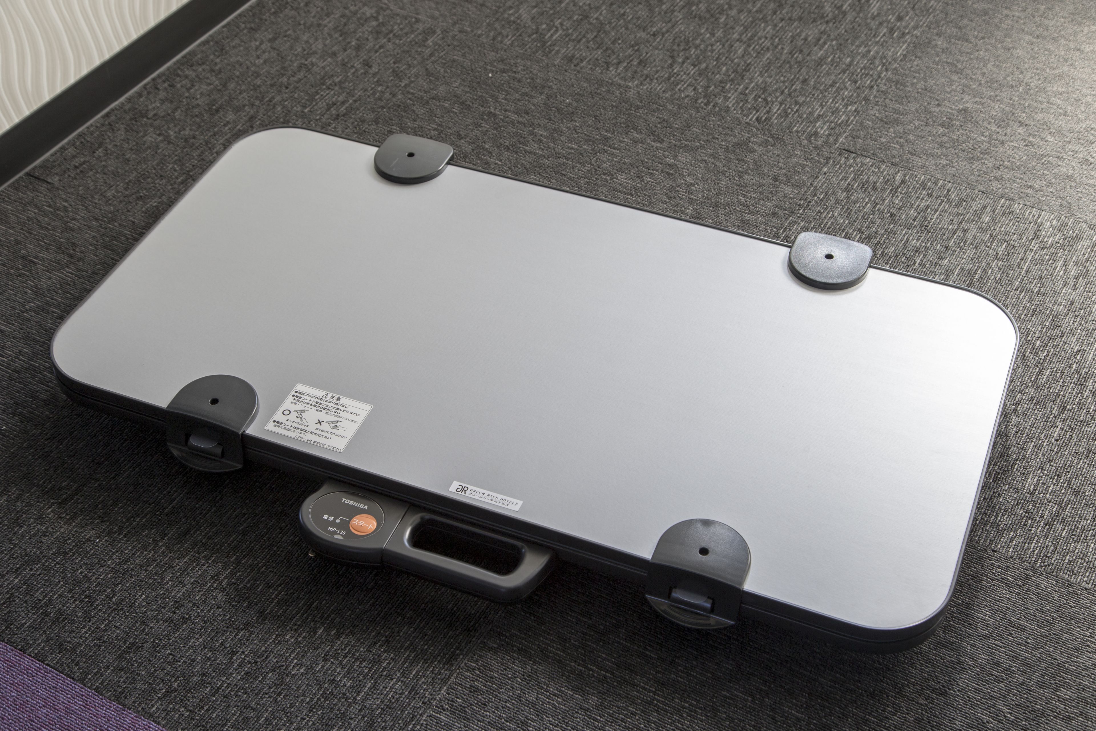 Un ordinateur portable orné d’un autocollant indiquant qu’il s’agit d’un modèle Toshiba, posé sur une surface texturée.