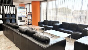 Um lobby moderno com sofás de couro, uma máquina de café e um refrigerador automático.