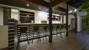 A modern bar area with wooden slats, bar stools, and a counter.