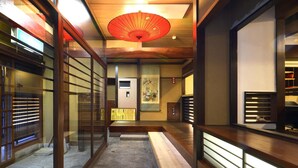 A hallway with wooden flooring, a bench, and a red umbrella hanging from the ceiling.