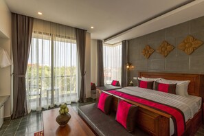 A hotel room with a large bed, a wooden headboard, and a view of the outdoors through sheer curtains. - Silver Palms Residence (Siem Reap)