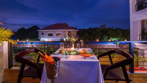 A table set for two with a bottle of champagne, a candle, and a glass of water. - Silver Palms Residence (Siem Reap)