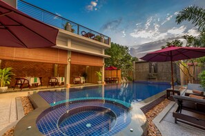 A swimming pool with a sunken area, outdoor seating, and a restaurant with tables and chairs. - Silver Palms Residence (Siem Reap)