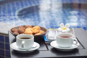 A tray with two cups of coffee and a bowl of pastries on a table near a pool. - Silver Palms Residence (Siem Reap)