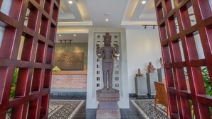 A statue in a hallway with a brick wall and a tiled floor. - Silver Palms Residence (Siem Reap)