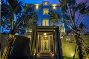 Een modern gebouw met een trap naar een deur, palmbomen en een bord met de tekst 'Silver Palms Residence'.
