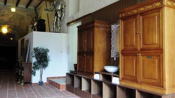 A spacious hallway with a wooden cabinet, a potted plant, and a tiled floor.