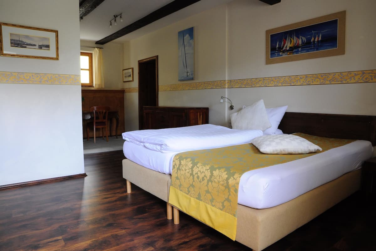 Ein Hotelzimmer mit einem grossen Bett, Holzboden und einem Essbereich im Hintergrund.