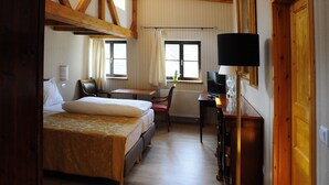 A room with two beds, a desk, a chair, a television, and a lamp. - Hotel Schlossresidenz Heitzenhofen (Duggendorf)