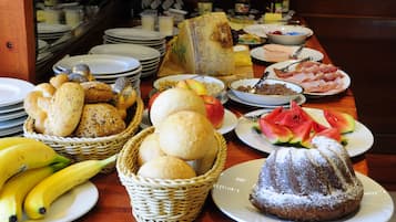 Ein Buffet mit verschiedenen Speisen, darunter Brot, Obst und Desserts.