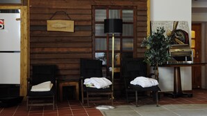 A room with wooden walls, a black floor lamp, two chairs with towels, a small table, and a grill. - Hotel Schlossresidenz Heitzenhofen (Duggendorf)