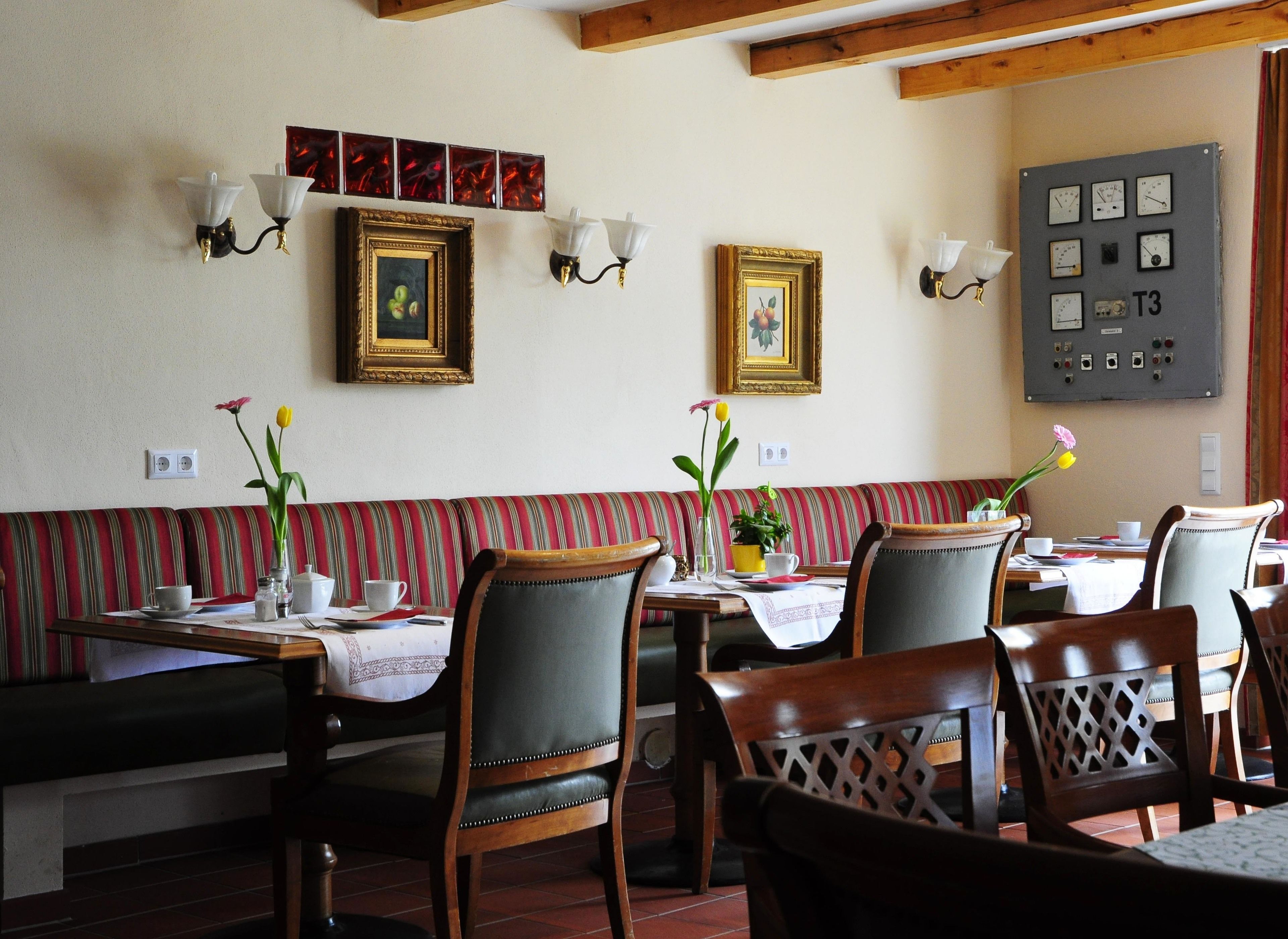 A dining area with striped benches, wooden chairs, and tables set for dining.