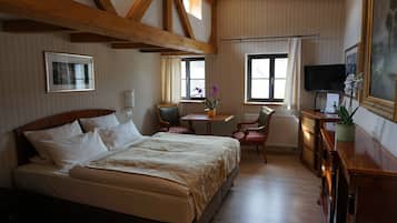 Una habitación de hotel con una cama grande, un escritorio con una silla, un televisor y una ventana con cortinas.