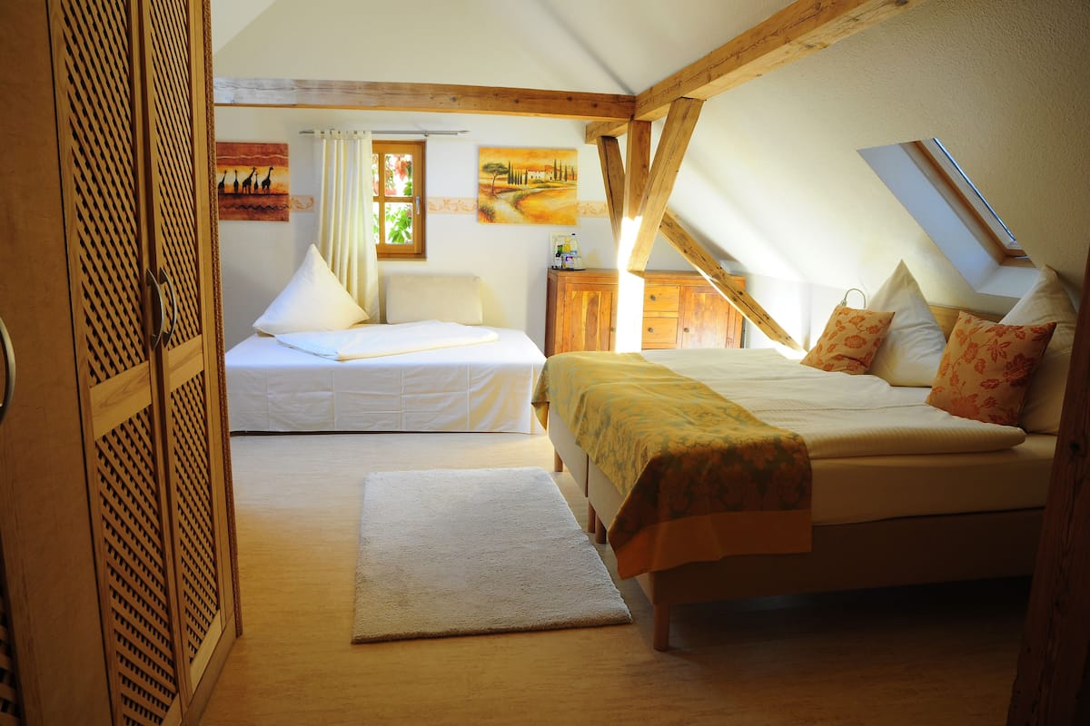 Ein Schlafzimmer mit zwei Betten, Holzbalken, einem Oberlicht und Kunstwerken an den Wänden.
