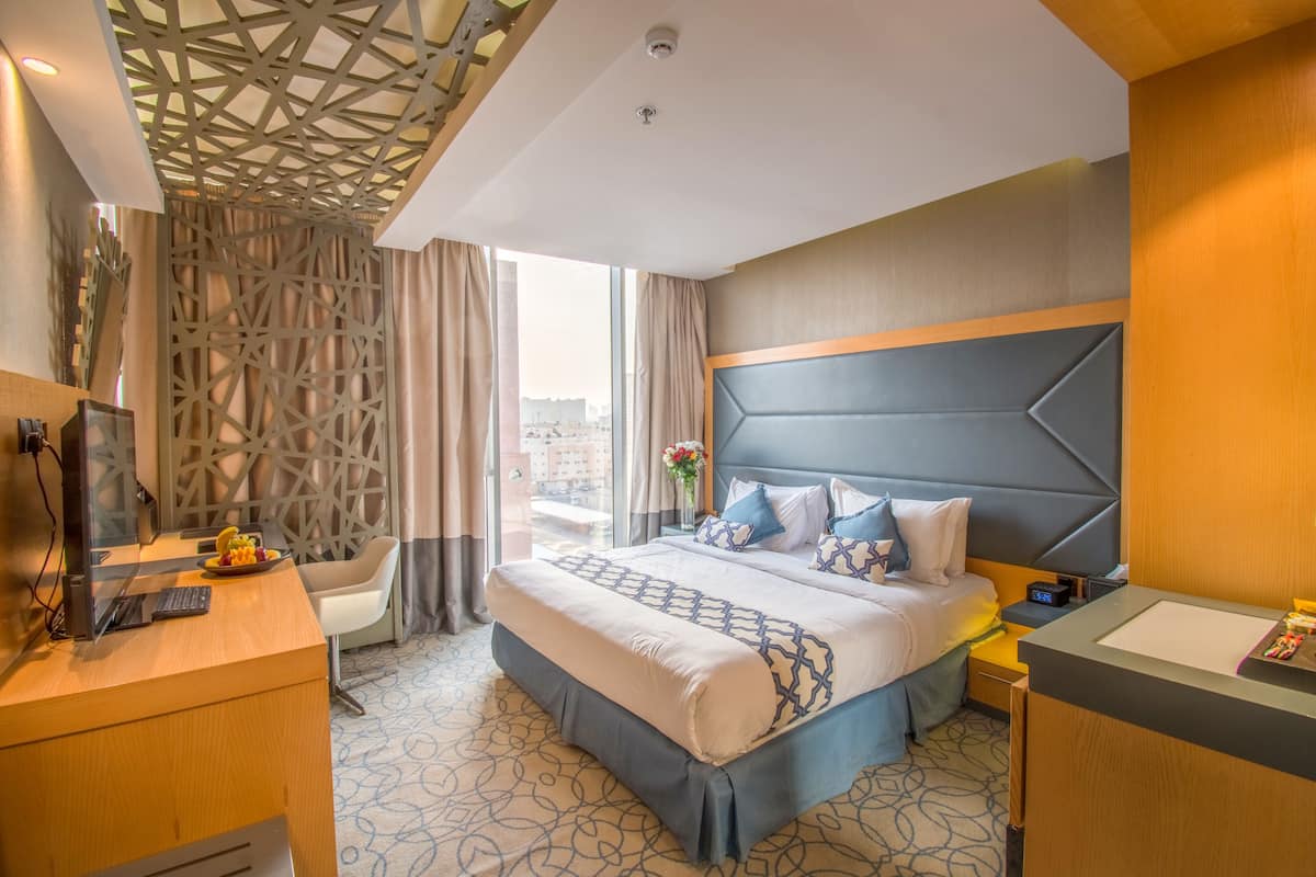 Ein modernes Hotelzimmer mit einem großen Bett, einem Schreibtisch, einem Stuhl und einem Badezimmer.