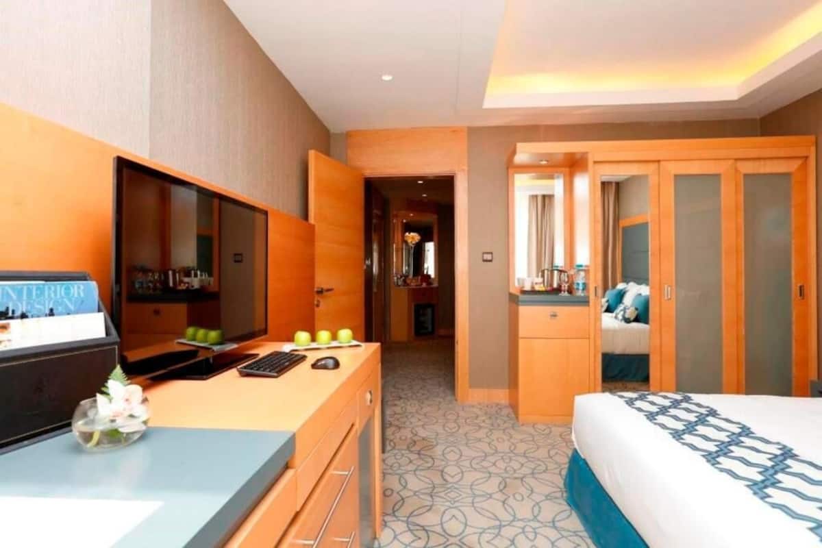 Ein Hotelzimmer mit einem Bett, einem Schreibtisch mit Computer, einem Spiegel und einem Kleiderschrank.