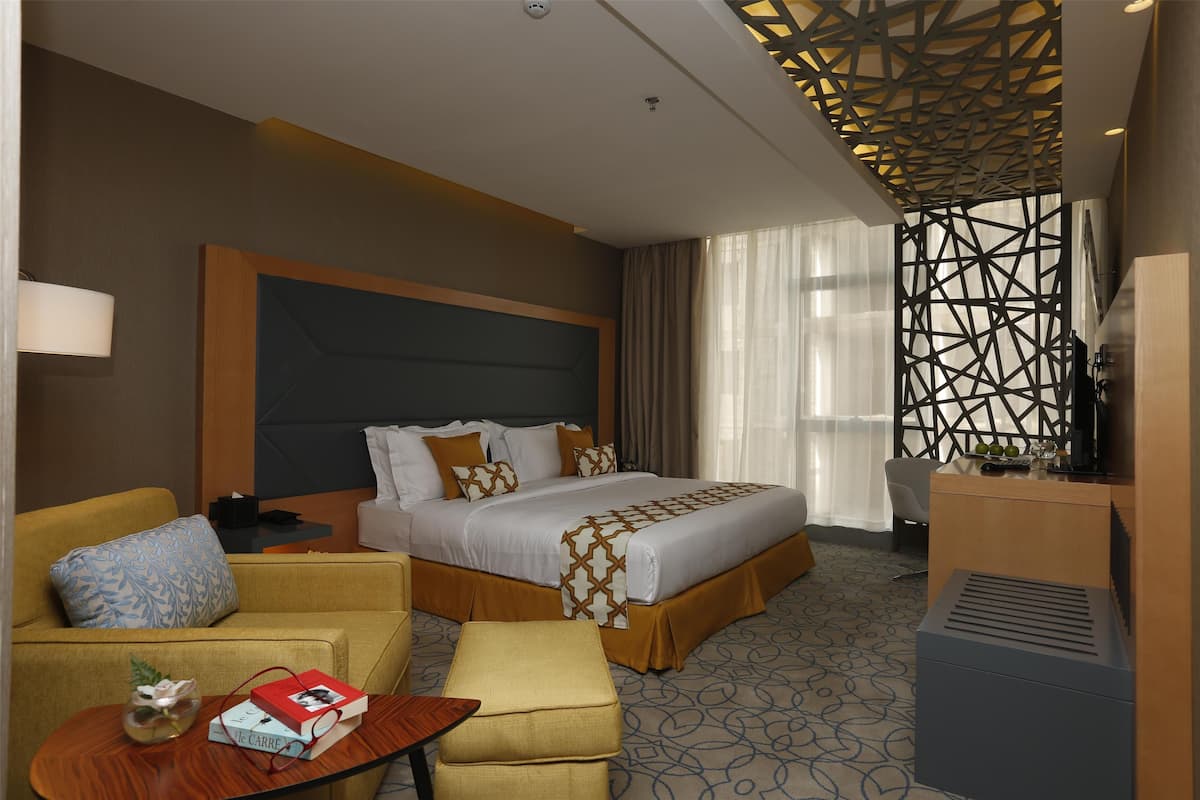 Ein Hotelzimmer mit einem großen Bett, einer Couch, einem kleinen Tisch und einem Schreibtisch.