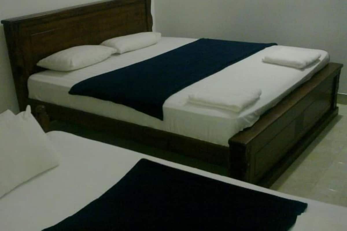 A single bed with a wooden headboard, white bedding, and a dark blue throw blanket.