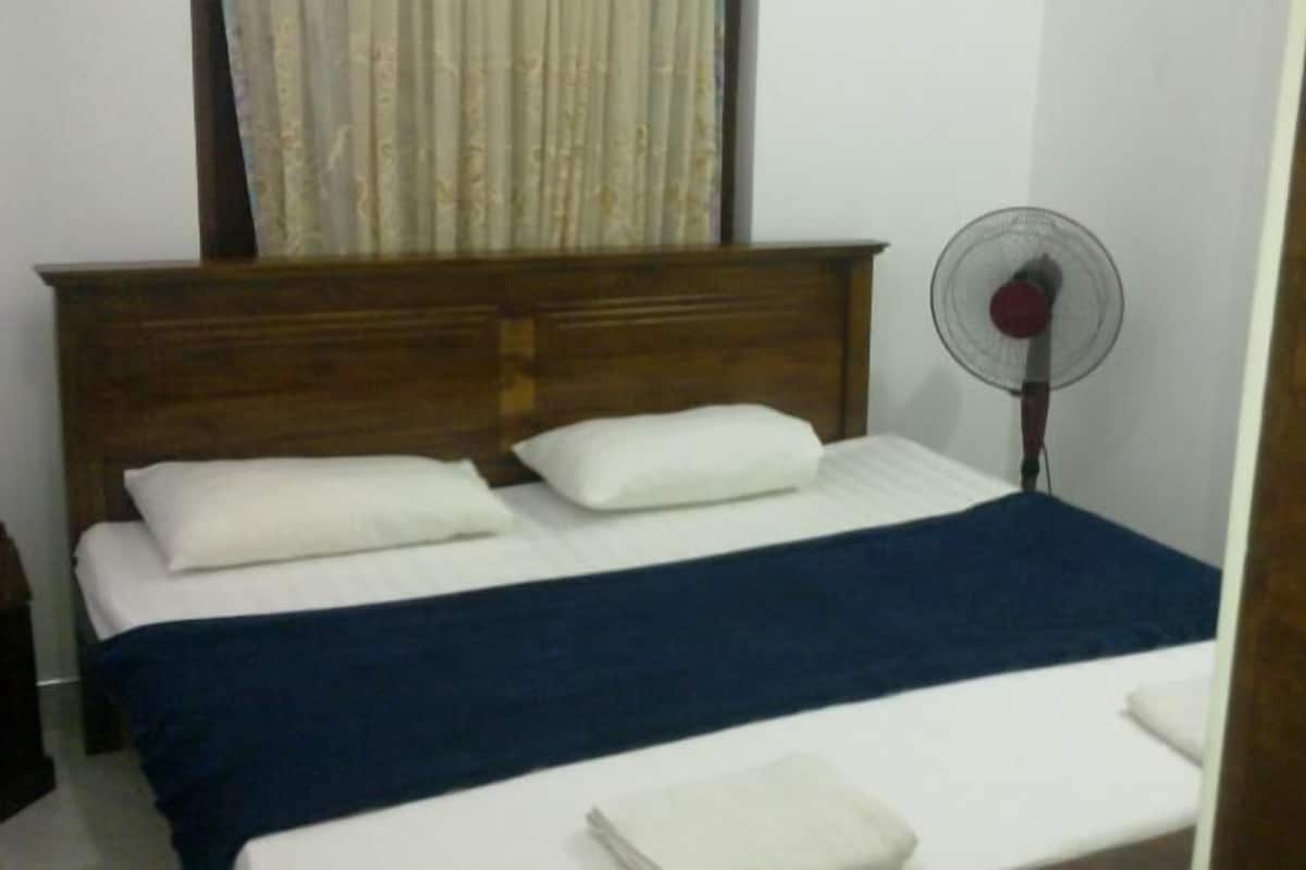 A neatly made bed with a wooden headboard, white pillows, and a blue blanket.