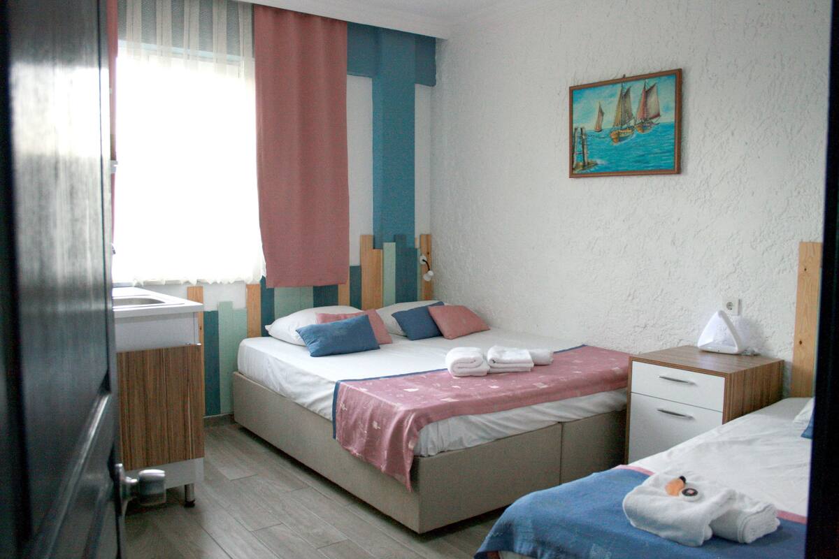 A bedroom with a bed, bedside table, and a painting on the wall.