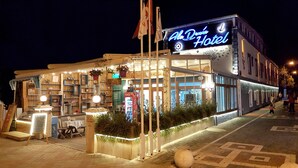 A hotel with a neon sign, outdoor seating area, and a Coca-Cola refrigerator. - AlaDeniz Hotel (Istanbul)