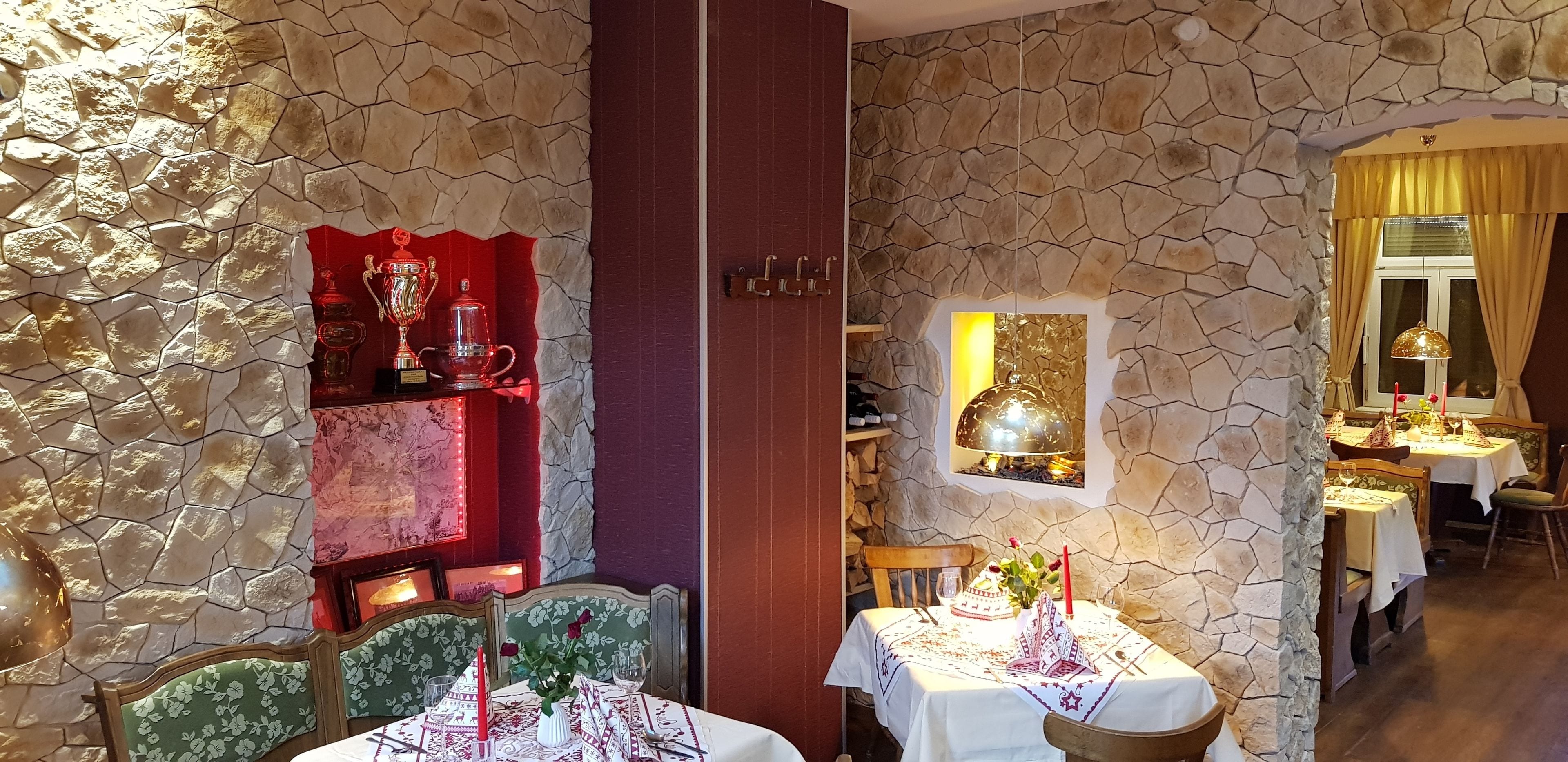 A restaurant with stone walls, wooden furniture, and tables set for dining.
