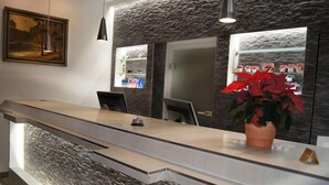A reception desk with a stone facade, a potted plant, and a framed painting on the wall. - Hotel Mohr & SPA (Werder (Havel))
