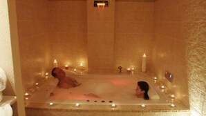 A spa room with a large bathtub, candles, and a person relaxing. - Hotel Mohr & SPA (Werder (Havel))