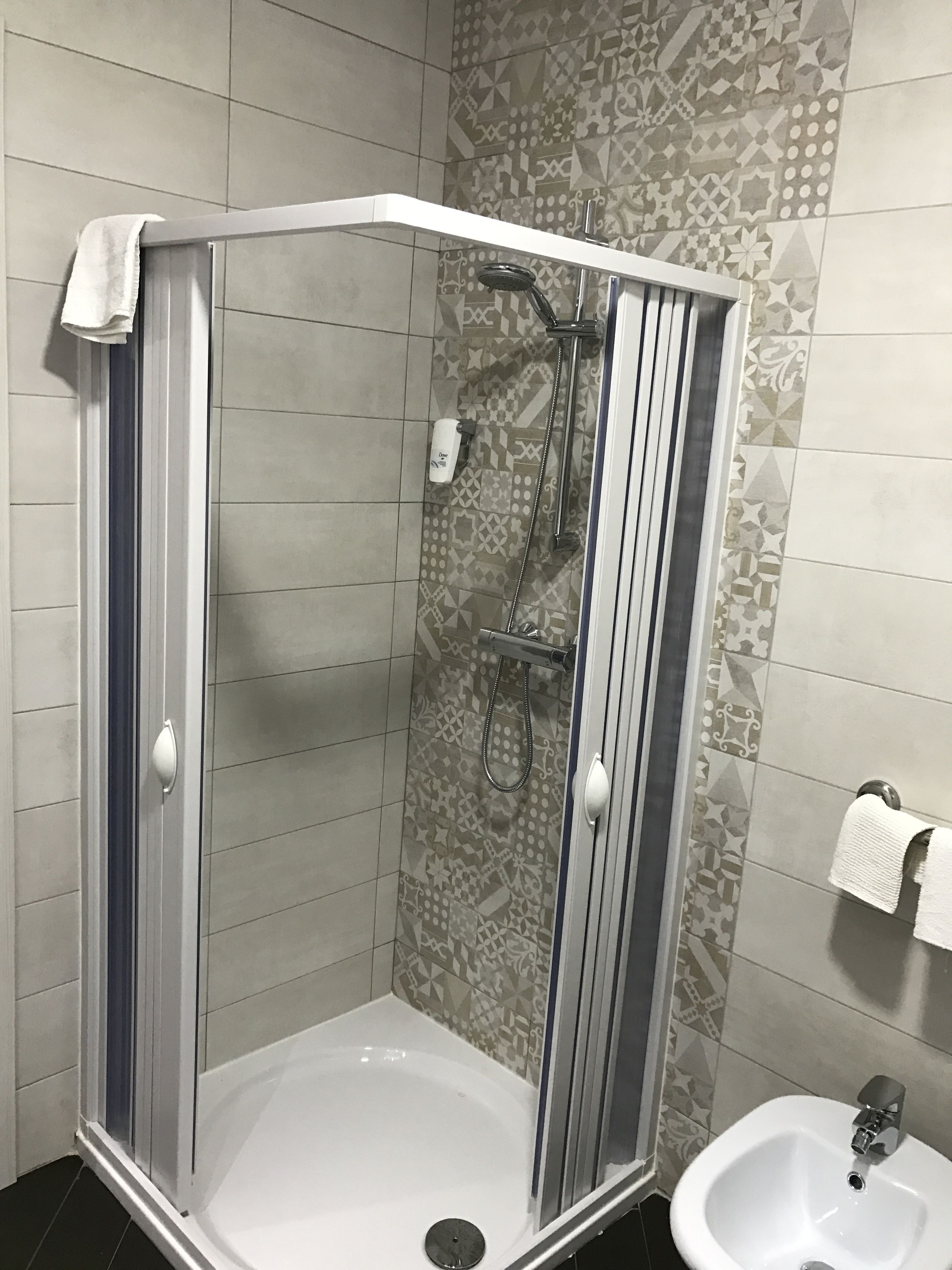 A glass-enclosed shower stall with a white sink and a towel hanging on the wall.