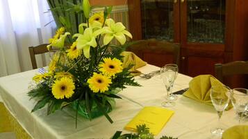 Una mesa de comedor decorada con un centro de mesa floral amarillo, un menú y copas de vino.