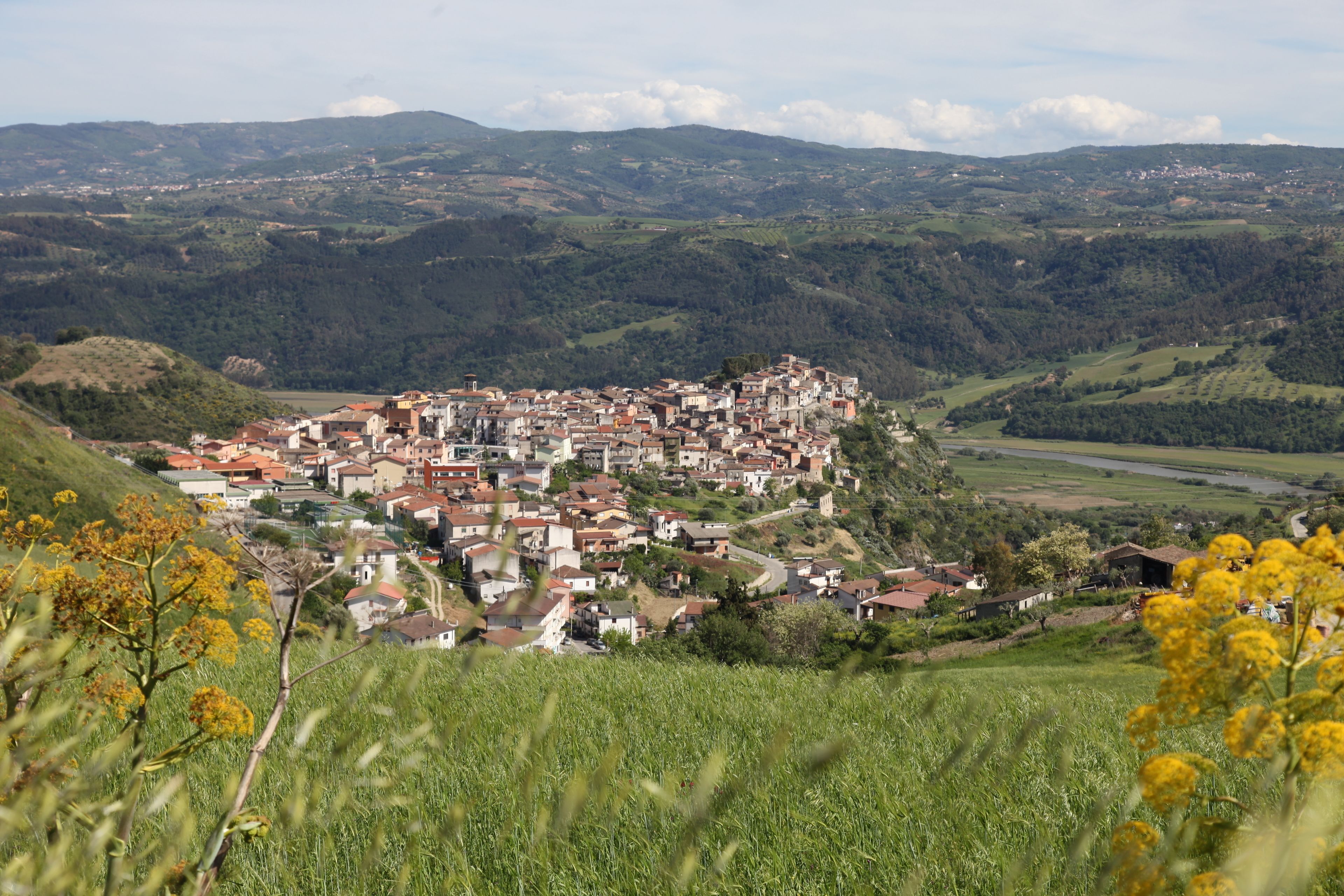 A hillside village with traditional buildings and a river in the background.