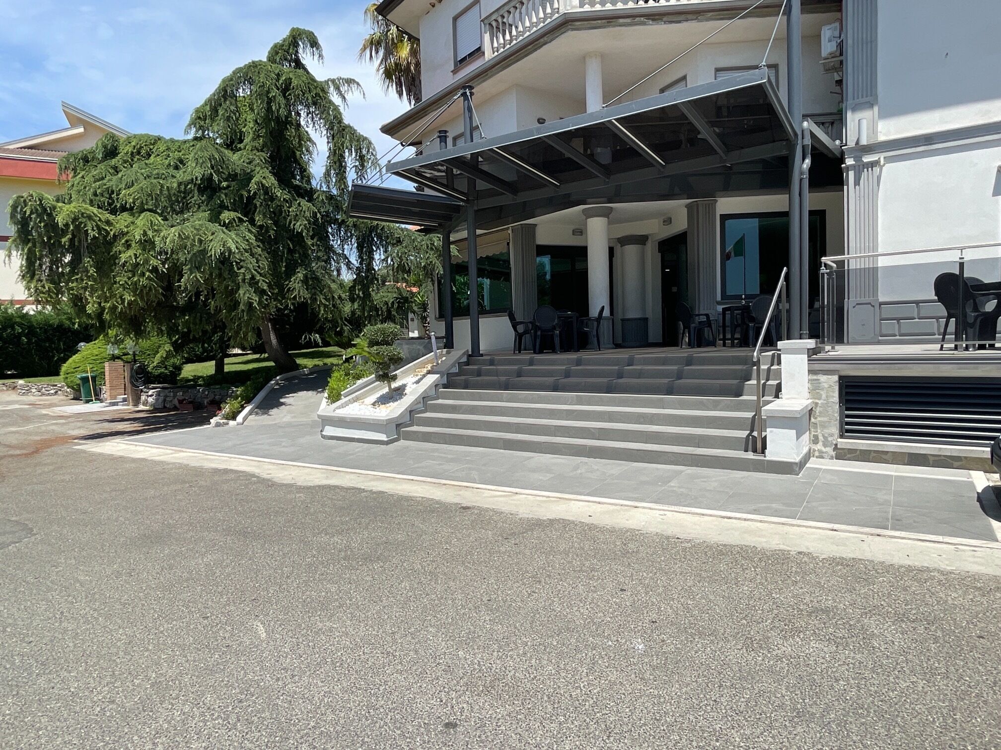 Ein Hotel mit Eingangsbereich und überdachter Außenbereich mit Sitzgelegenheiten sowie Treppen zum Eingang.