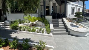 Un edificio moderno con un área exterior cubierta, escalones de piedra y diversas plantas.