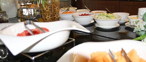 Una mesa de buffet con diversos alimentos y utensilios de servicio.