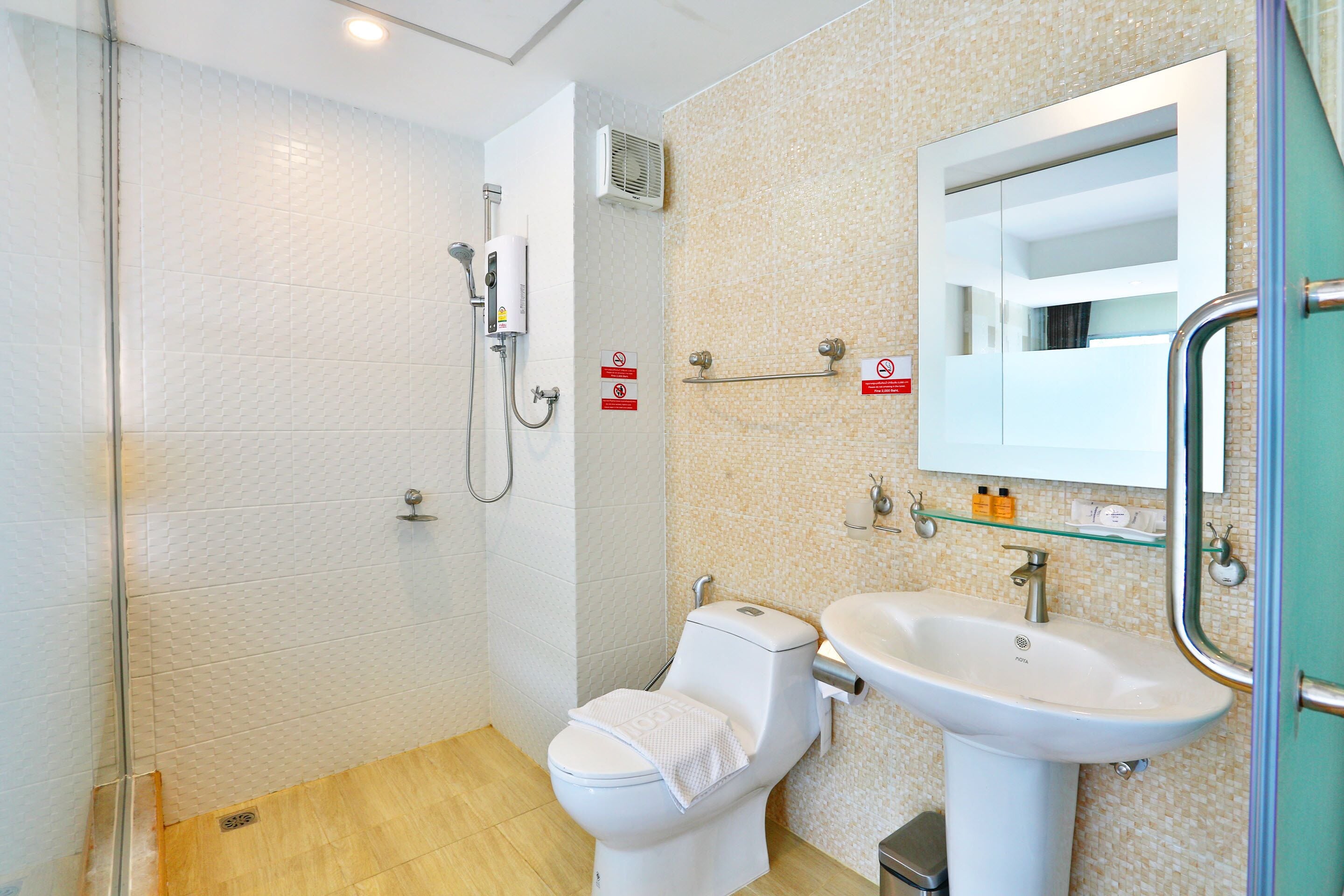 Une salle de bain équipée d’une douche, de toilettes, d’un lavabo et d’un miroir.
