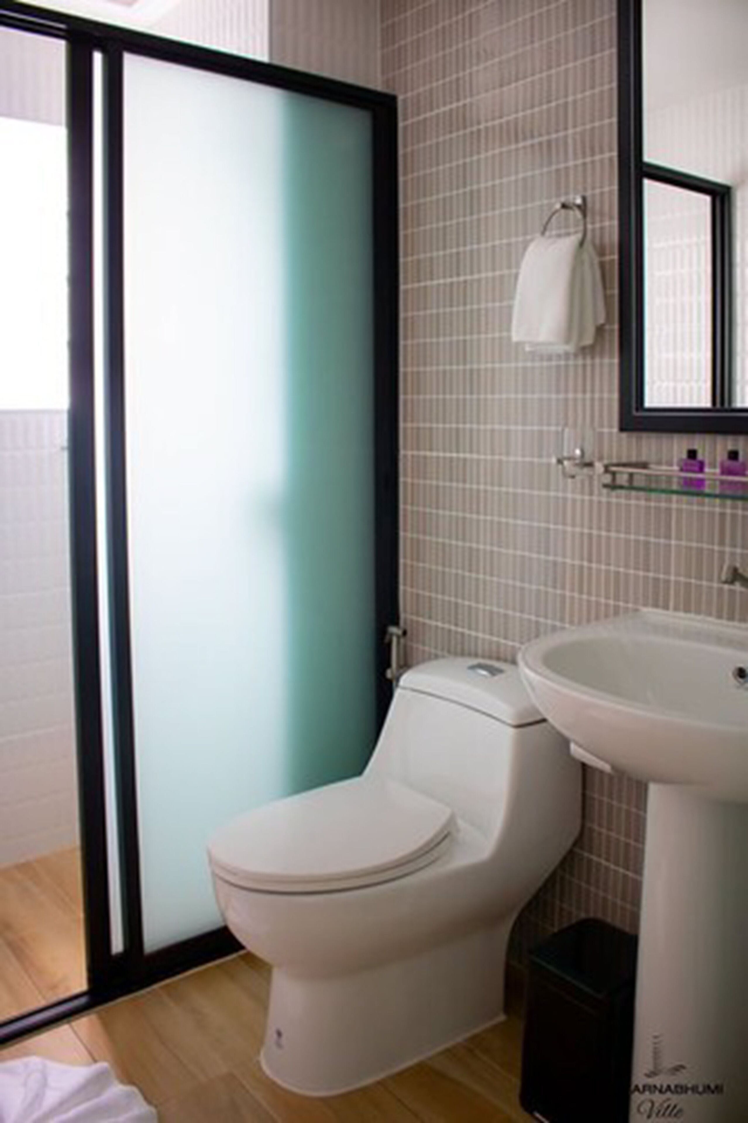 Un baño moderno con inodoro, lavamanos y cabina de ducha de vidrio.