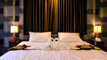 Hotelkamer met een bed, twee kussens, een nachtkastje met een lamp, en een muur met een geometrisch patroon.
